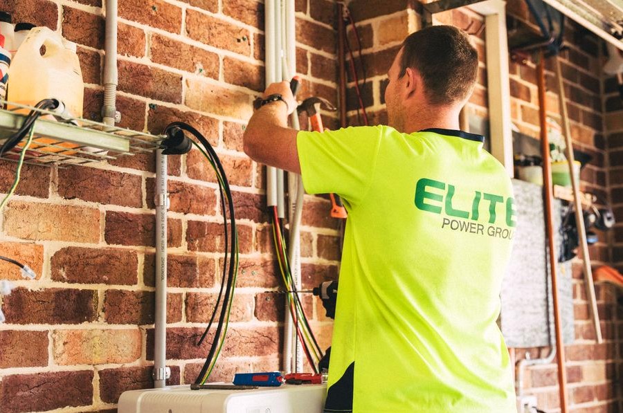 Electrician performing solar battery installation for sustainable energy storage in a home setting