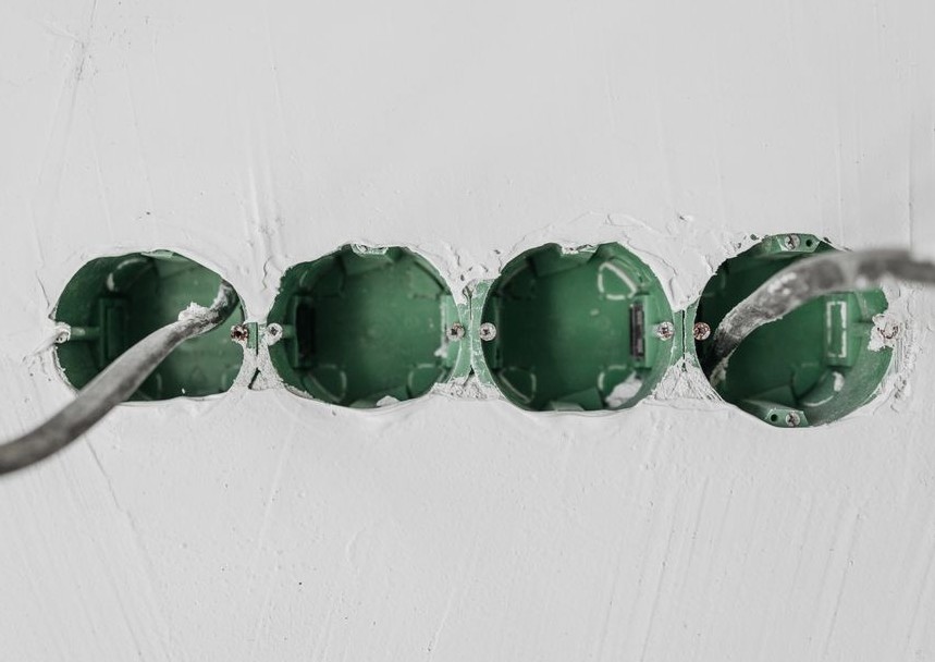 Close-up of green electrical boxes and wiring in a wall setup