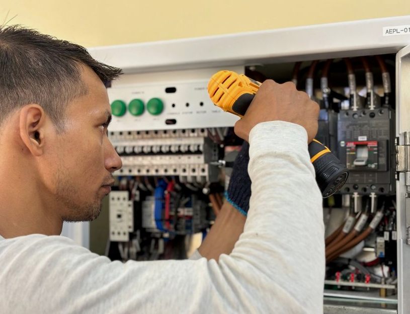 Professional electrician using a drill on an indoor circuit breaker panel